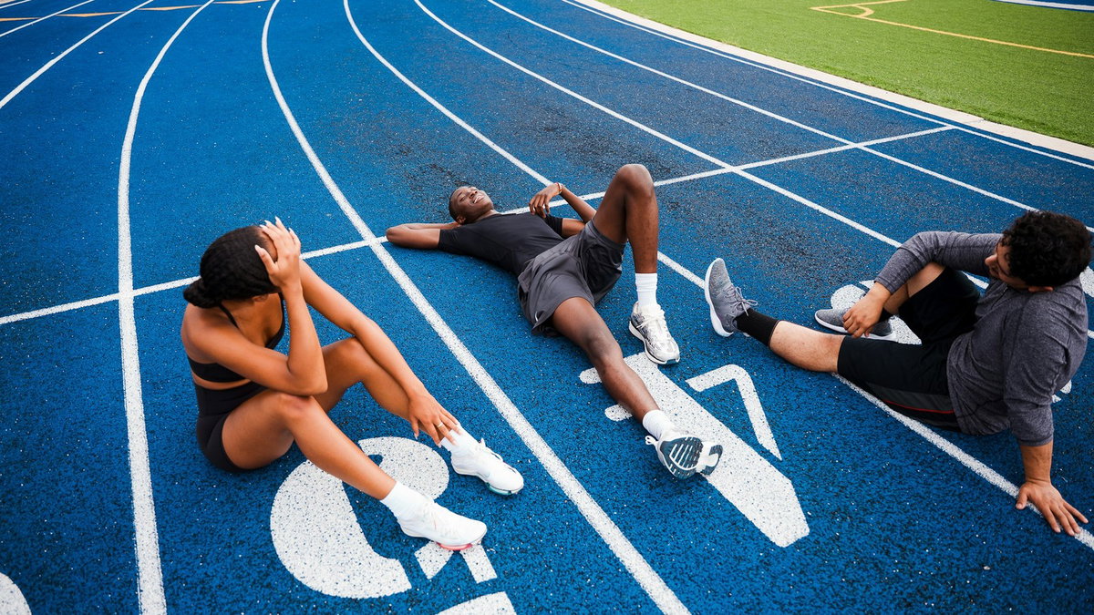 Athletes resting on a blue running track after training