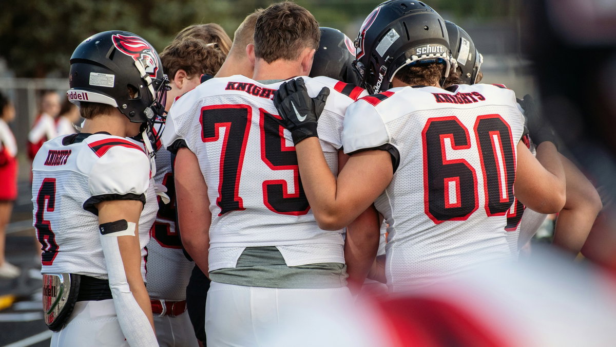 Coach resting a hand on a football player’s shoulder