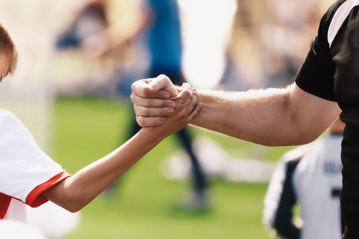 a coach and a player shake hands in solidarity